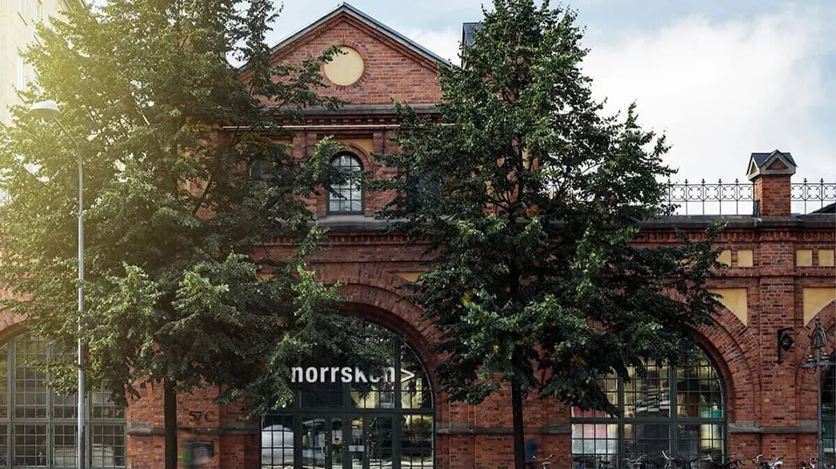 The red-brick façade of Norrsken House behind leafy trees – the Stockholm venue for the lunch seminar.