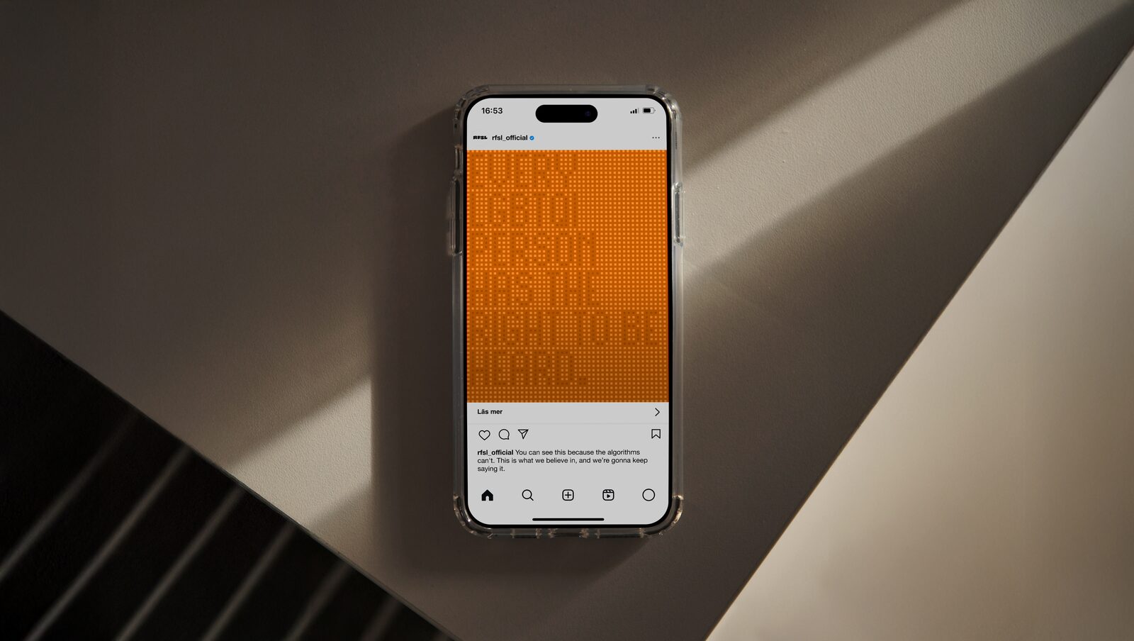 A phone on a sunlit concrete stairwell showing an orange pixel-text Instagram post from the Human writes font campaign.