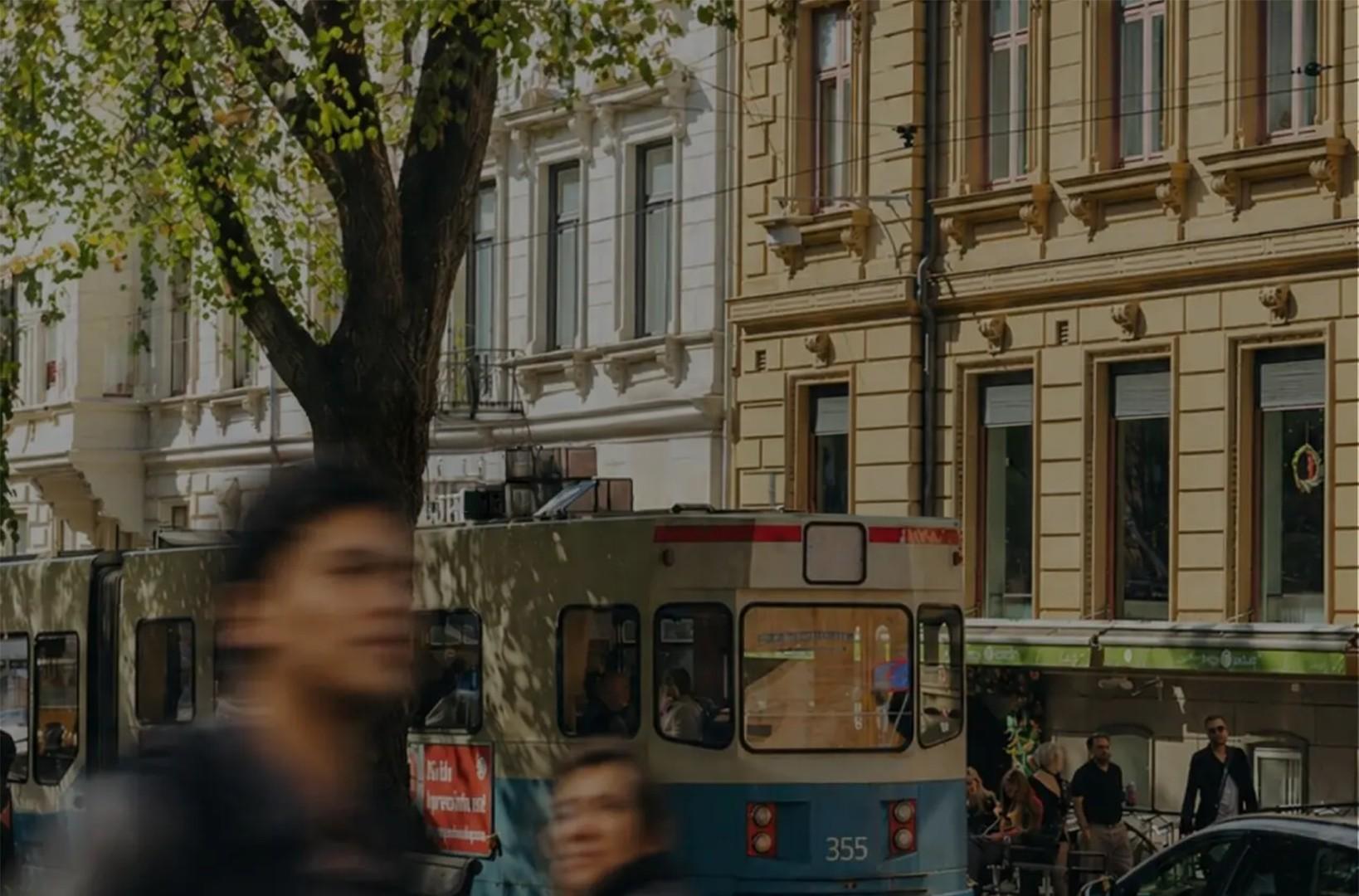 Photo of a Gothenburg street scene with a tram and pedestrians passing historic buildings.