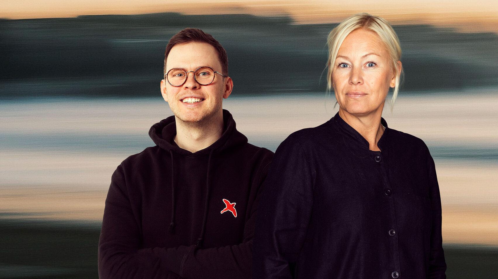 Portrait photo of a smiling man in a black hoodie with a red bird logo and a woman in a black jacket, standing side by side against a blurred dusk-toned backdrop.