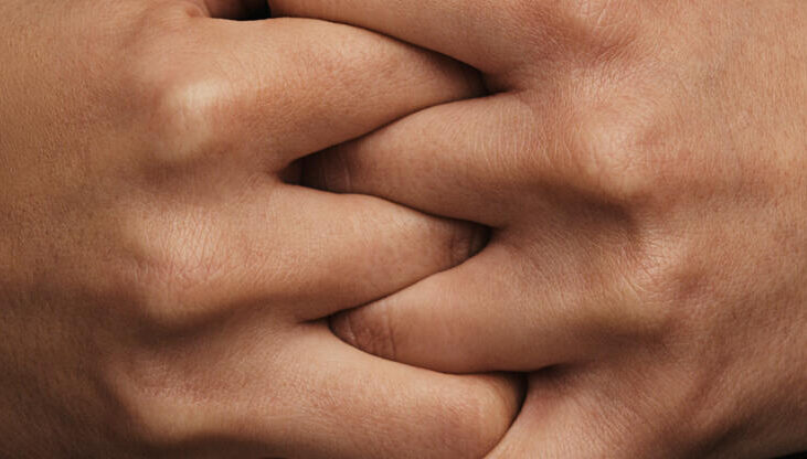 Two hands with fingers interlocked, filling the frame.